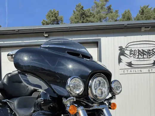A black Harley-Davidson outside the Buddies studio — chrome, headlights and paint side by side