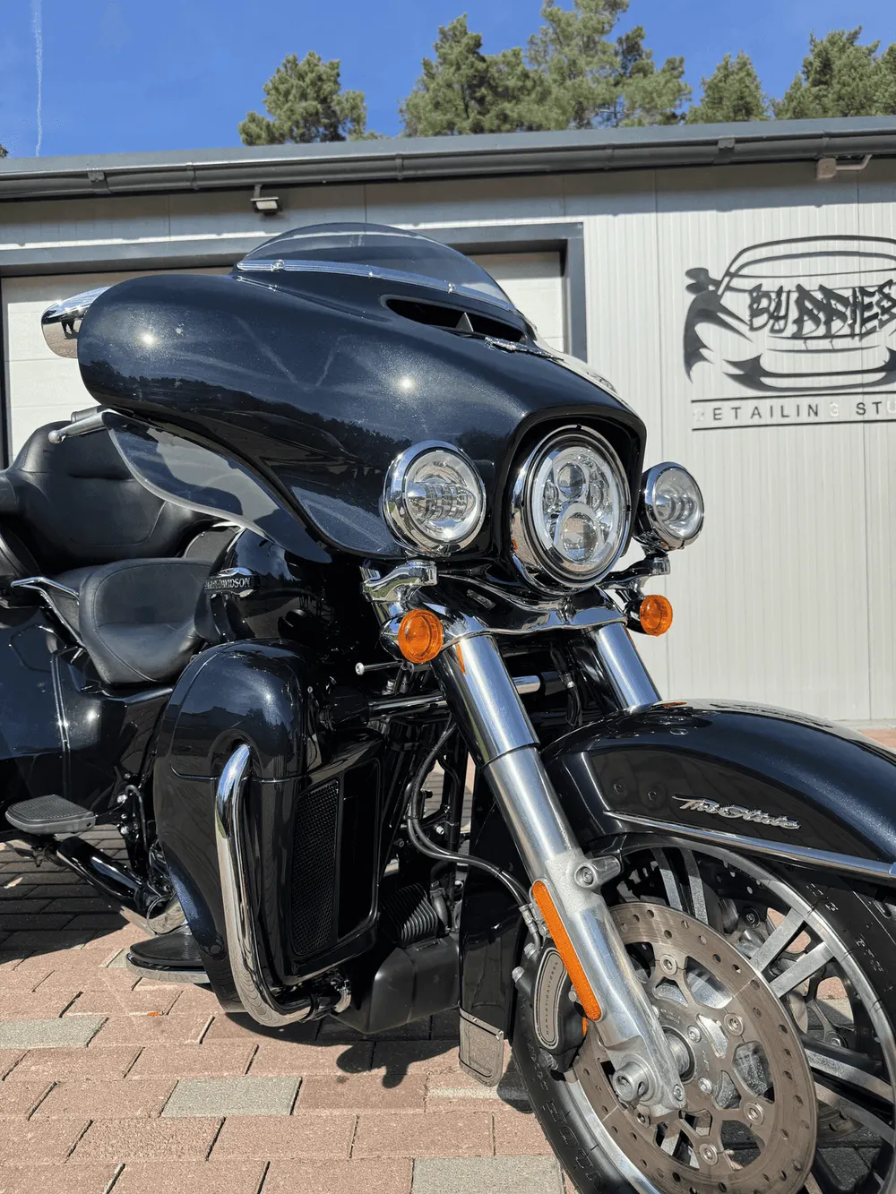 Eine schwarze Harley-Davidson vor dem Buddies Studio — Chrom, Scheinwerfer und Lack nebeneinander